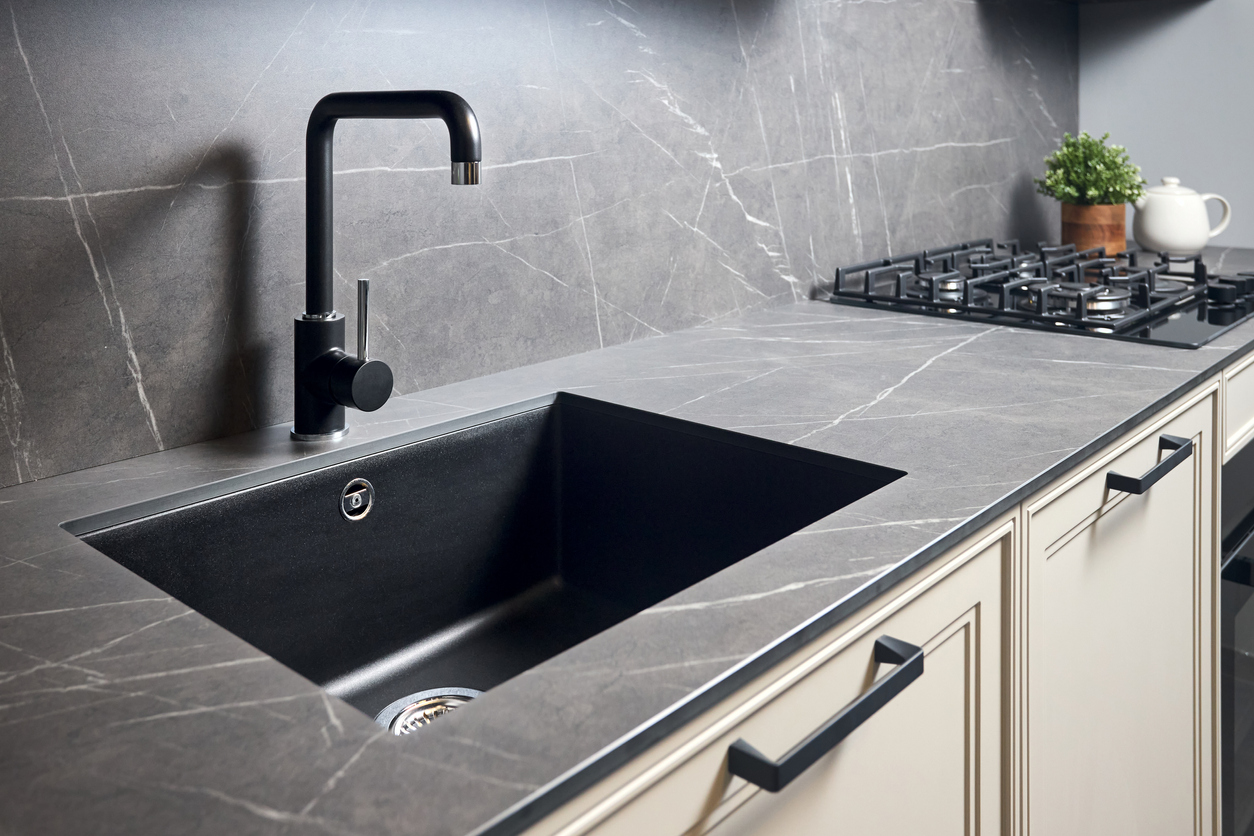 Black quartz countertop with white marbling and matching kitchen backsplash