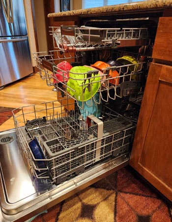 The KitchenAid FreeFlex dishwasher viewed from the side with the door open and all three racks out to show its capacity