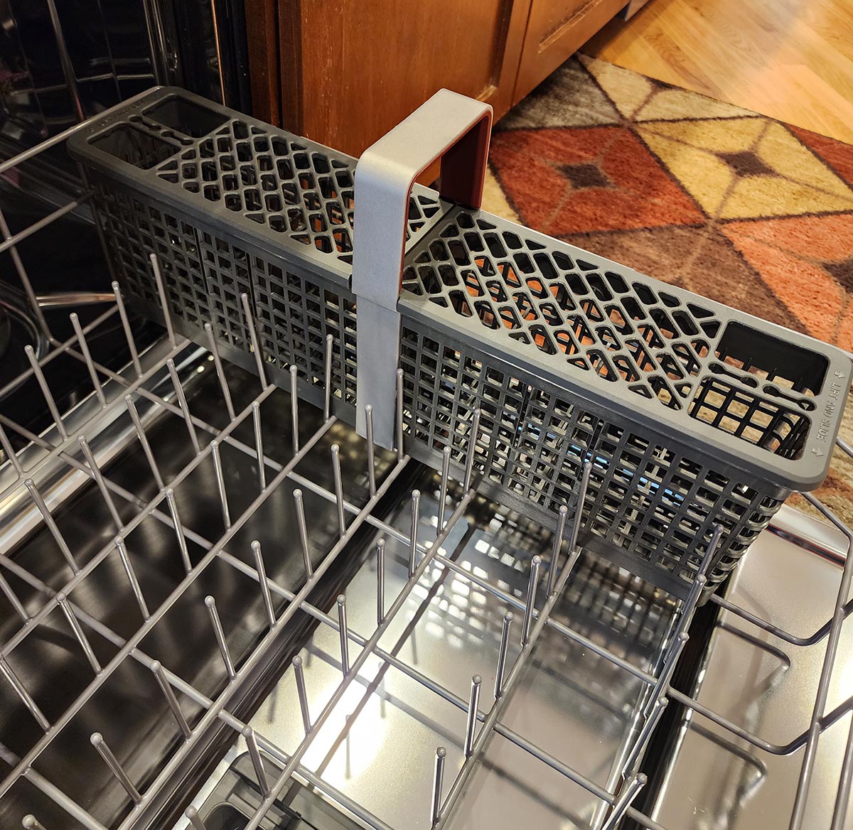 The bottom rack of the KitchenAid FreeFlex dishwasher extended with the utensil basket on one side