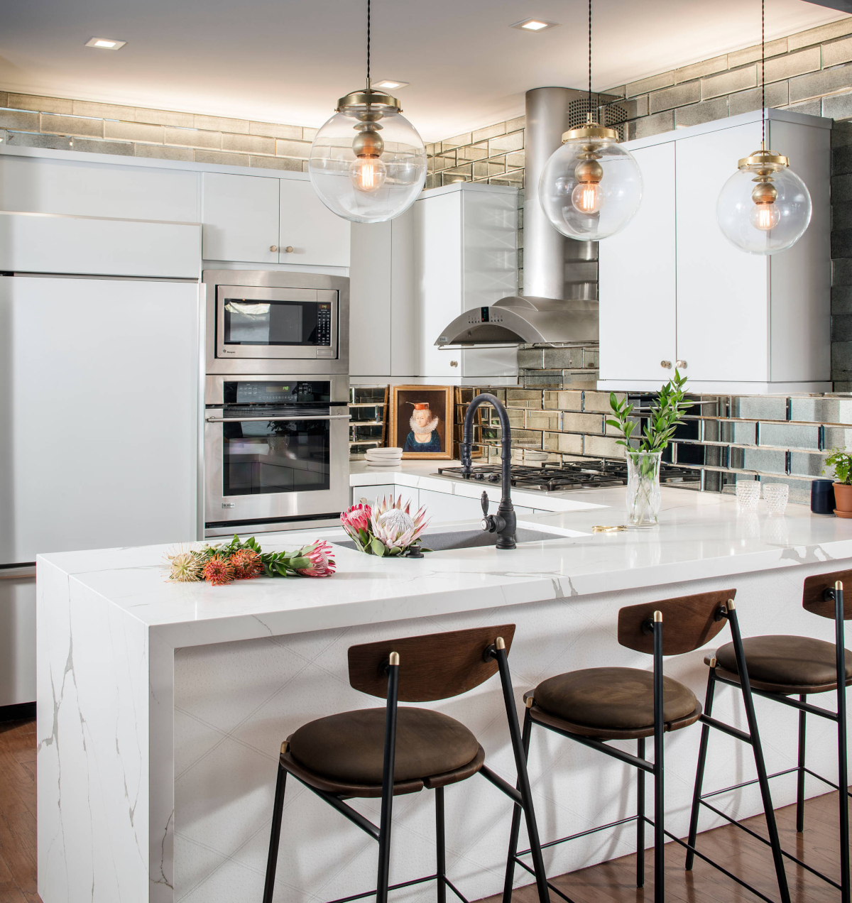 Kitchen with white cabinets, white marble countertops, and mirror tile backsplash
