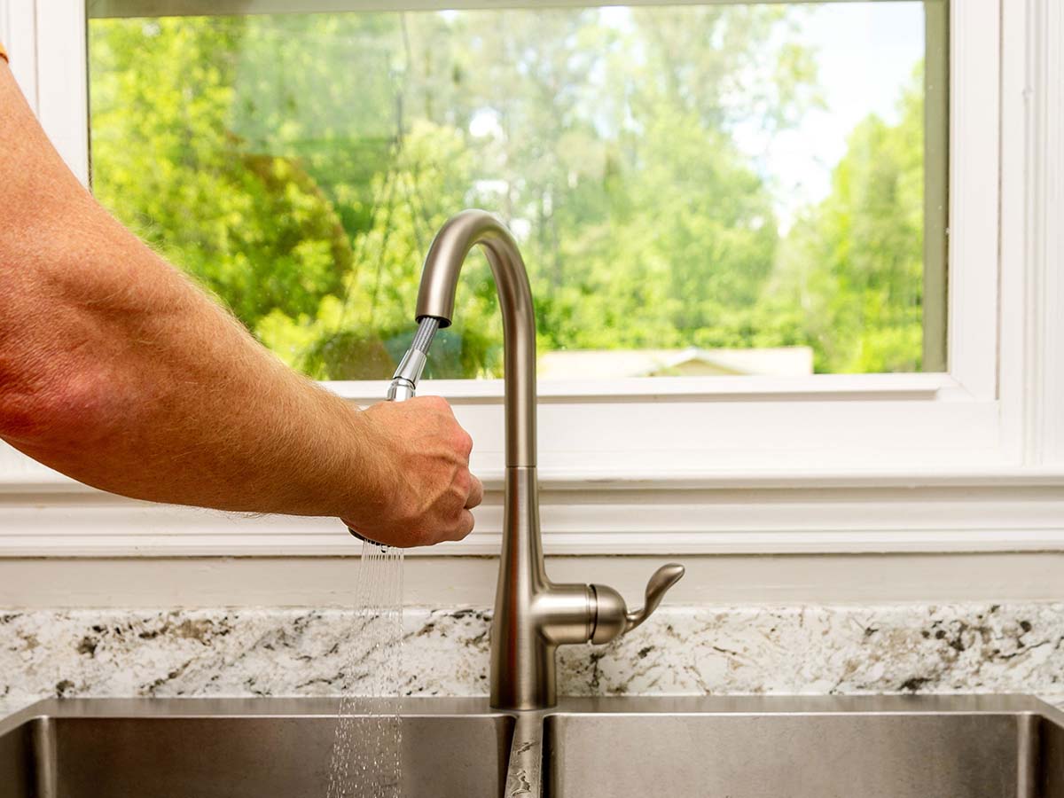 Man using the spray setting on the Moen Arbor kitchen faucet