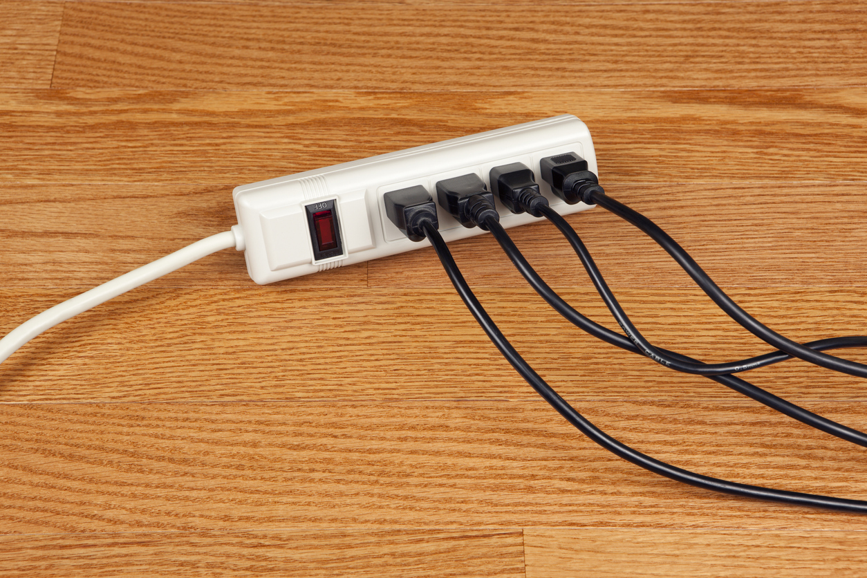 Small 4-outlet power strip with black cords plugged into each socket