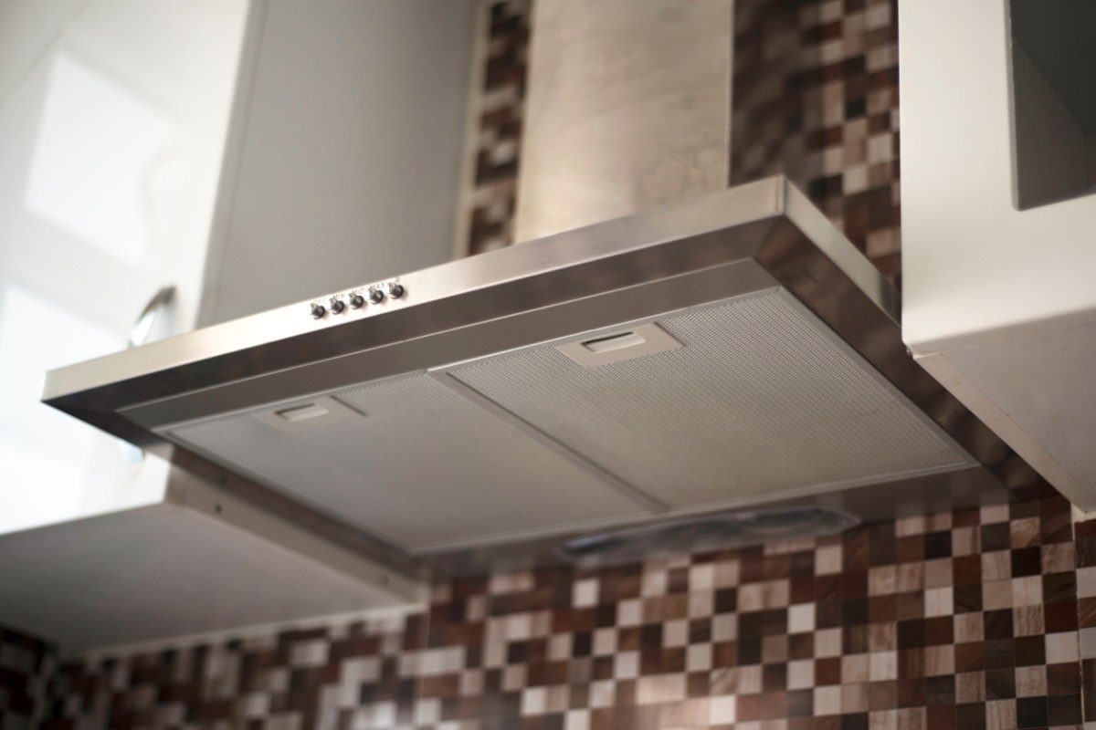 The underside of a ducted range hood mounted to a kitchen wall