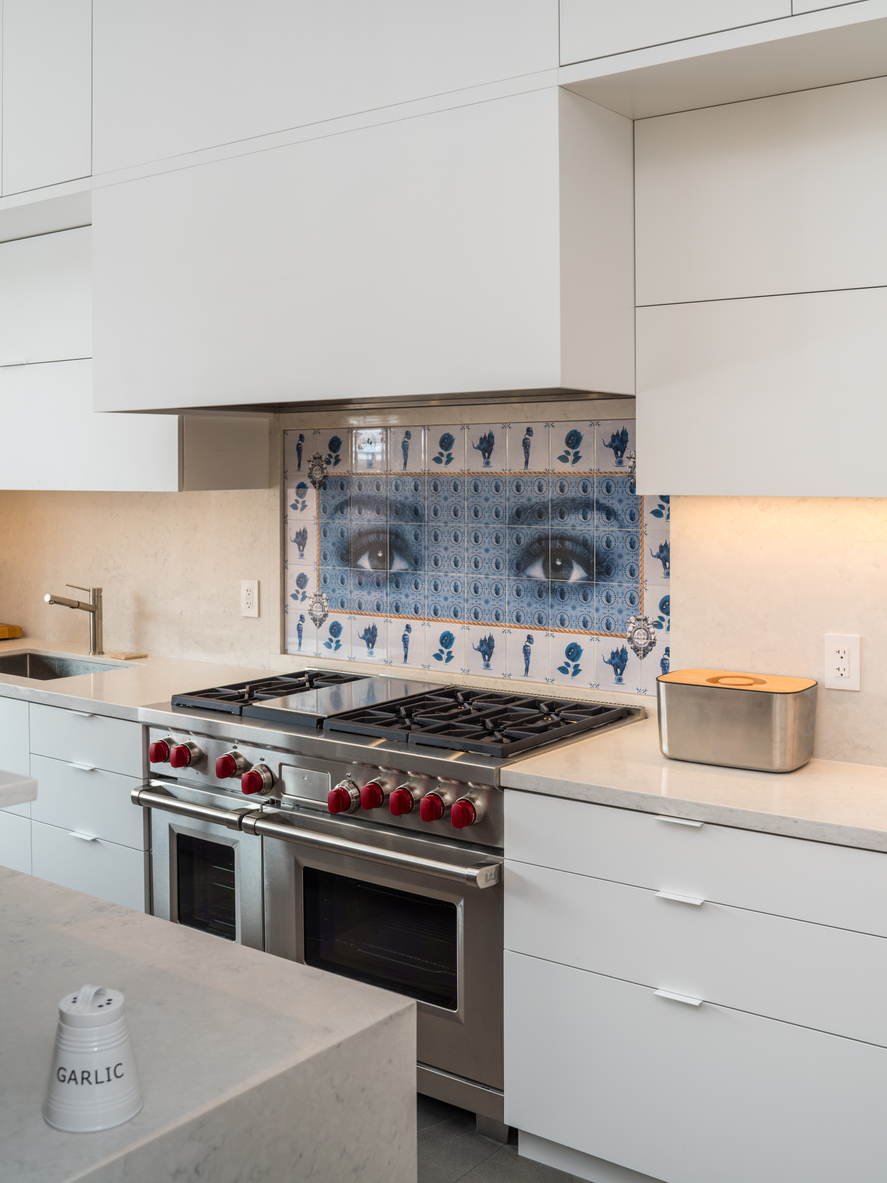 White kitchen with a blue-and-white stove backsplash tile mosaic depicting photorealistic eyes