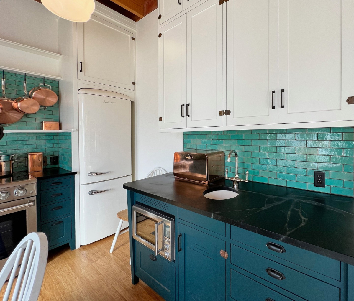 Stylish kitchen with teal tile backsplash, white and blue cabinets, and retro appliances