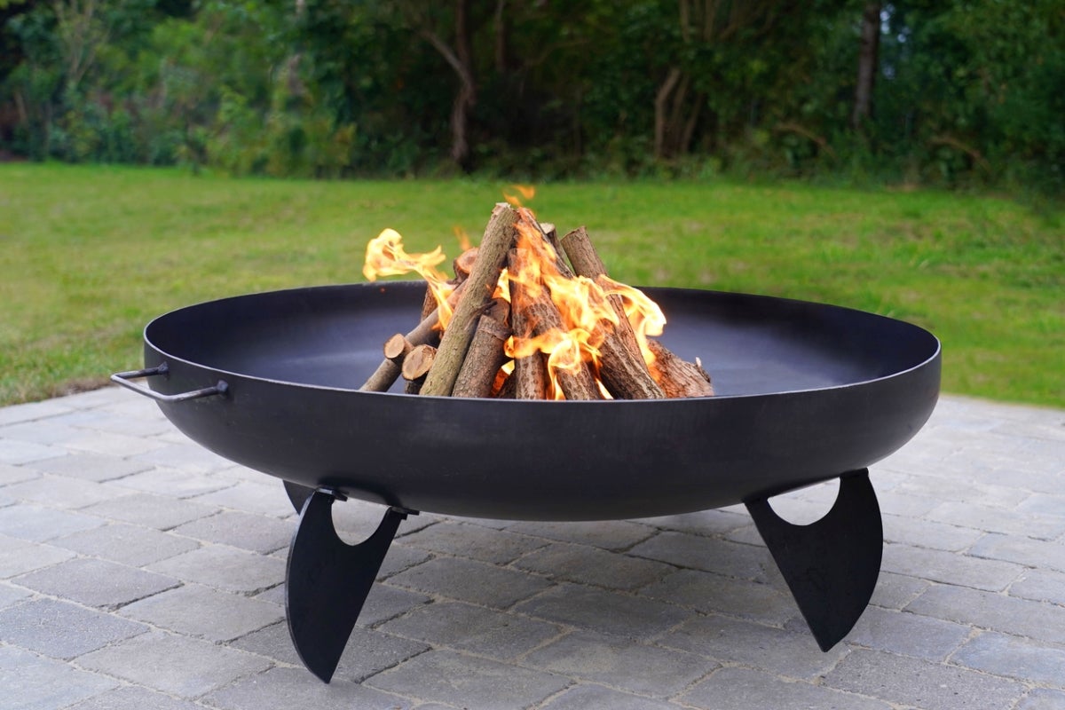 An outdoor fire pit on a cement patio burning a wood fire.