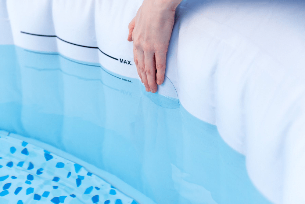 A hand attaching the best pool patch option to the interior side of an inflatable pool filled with water