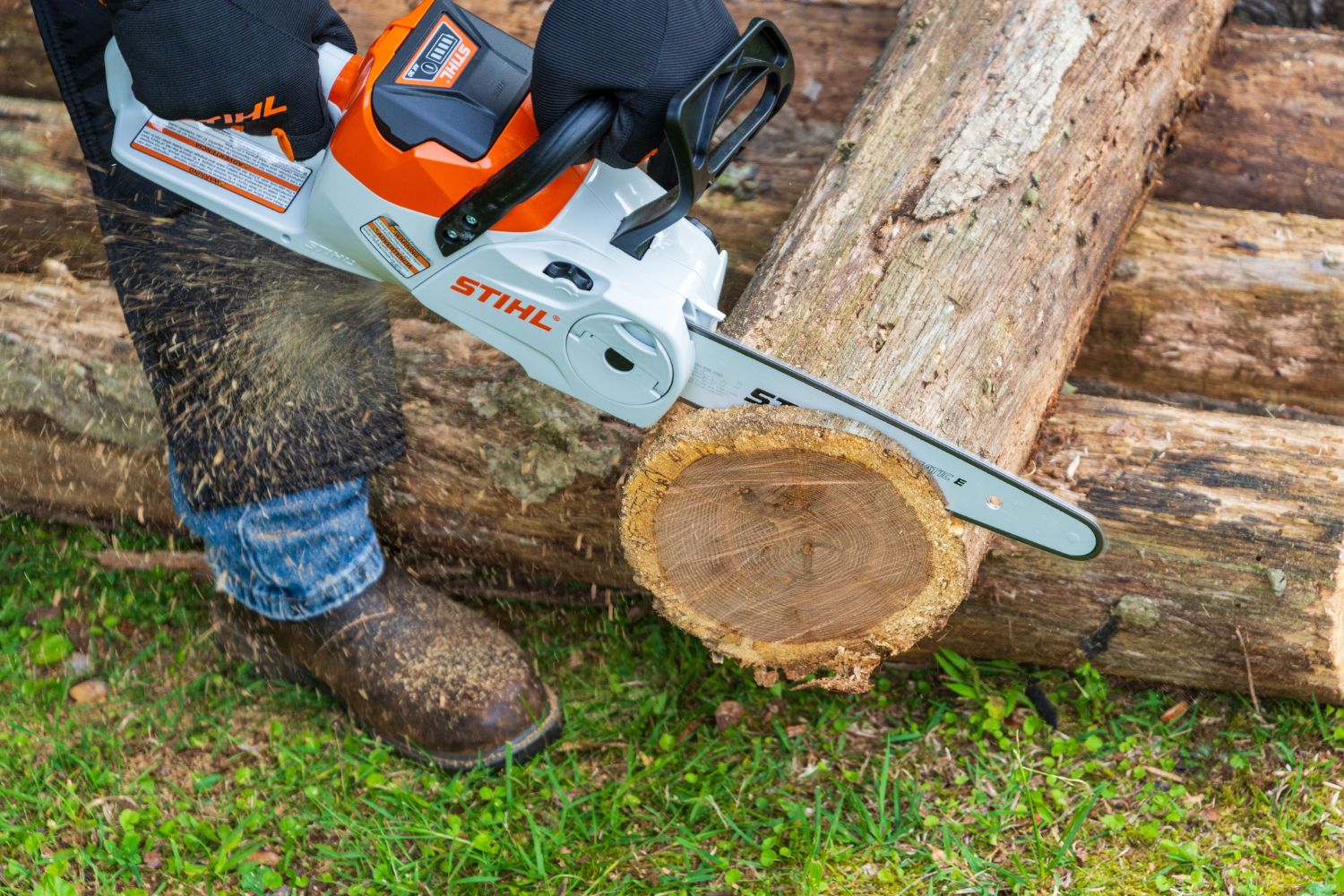 A person using the Stihl MSA electric chainsaw to saw the end off a log