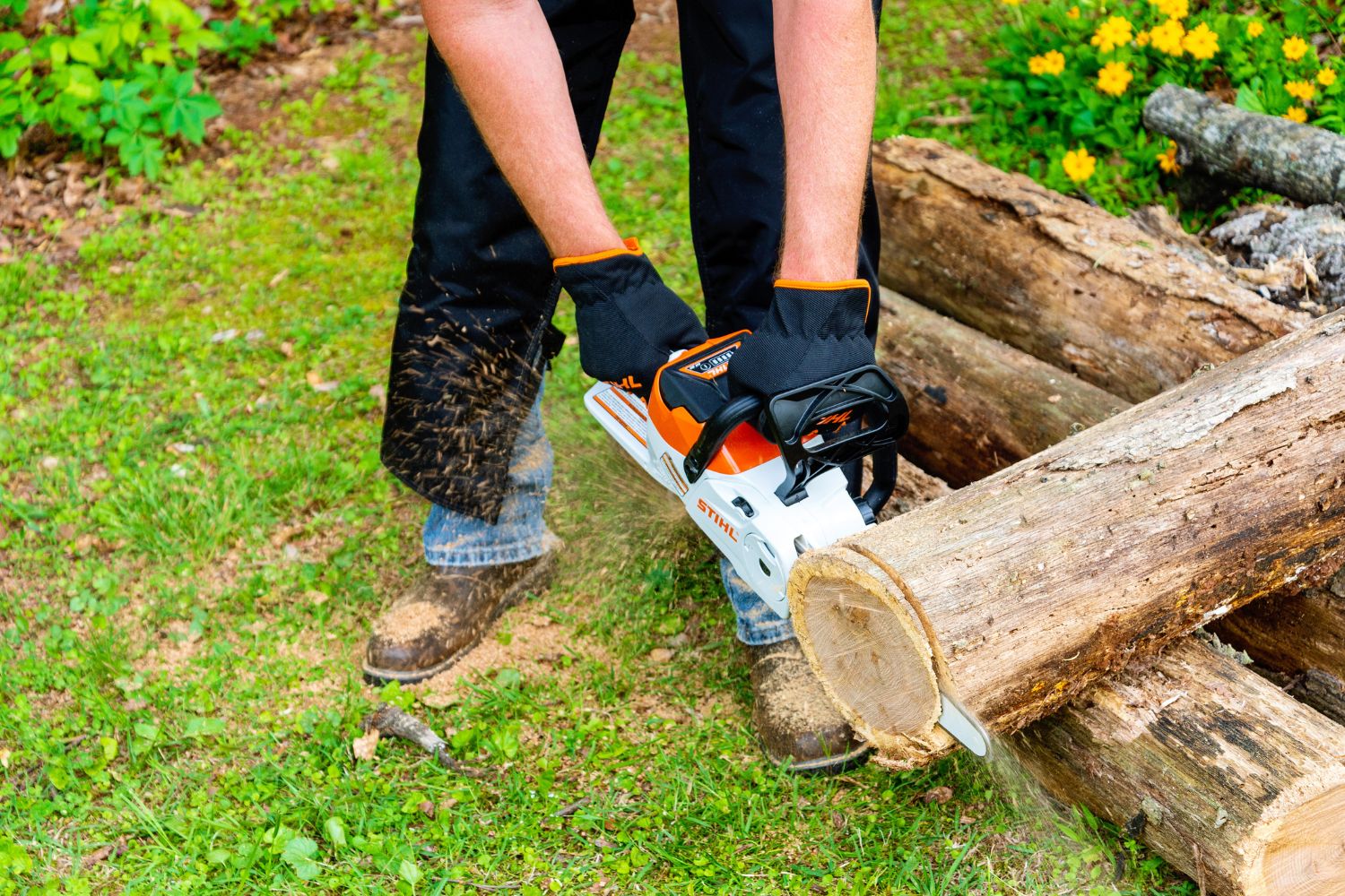 A person using the Stihl MSA electric chainsaw to saw the end off a log