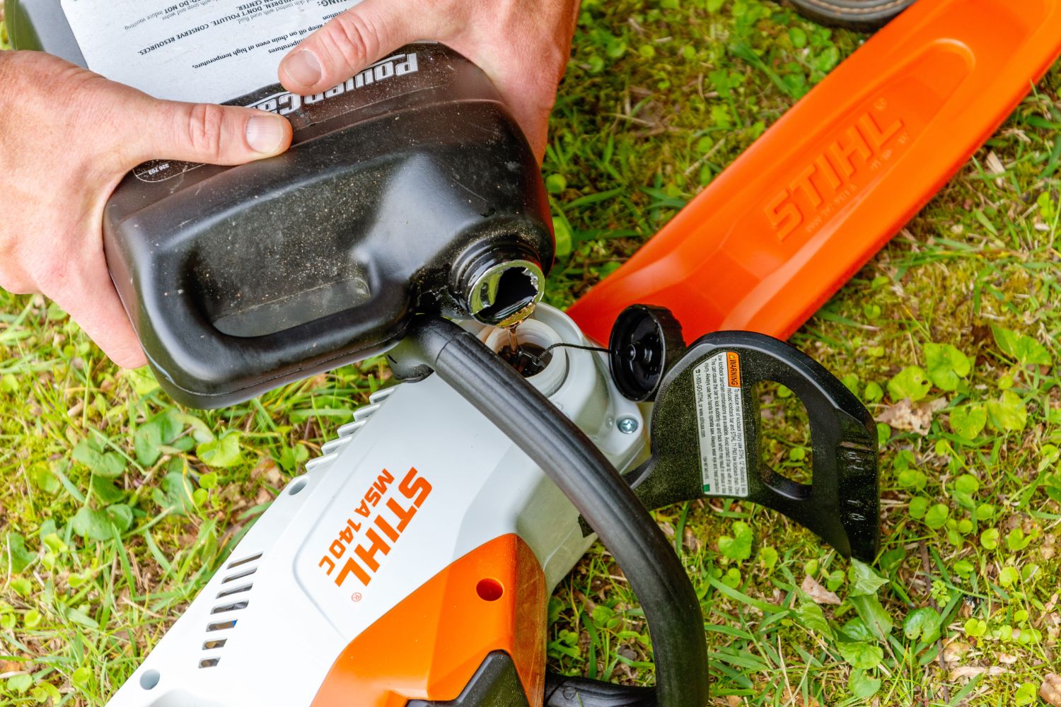 Someone adding oil to the Stihl MSA electric chainsaw