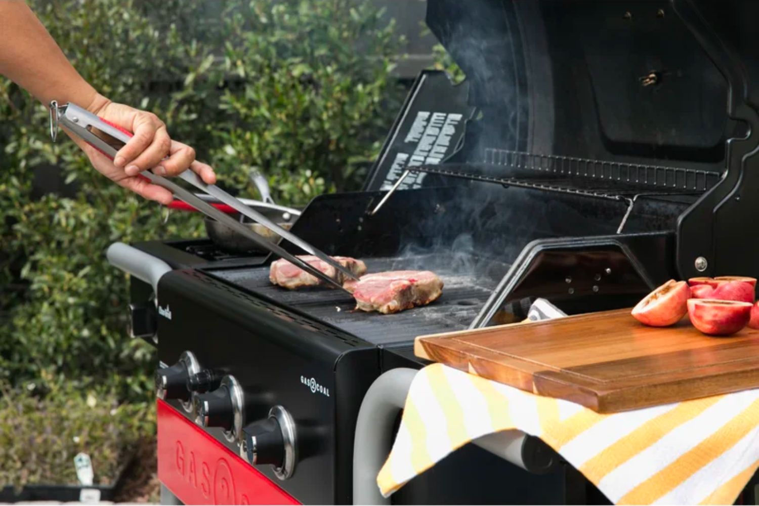 A grillmaster turning a cooking steak on the best hybrid grill option