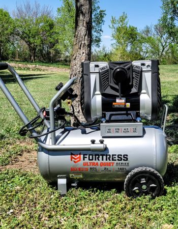 The highly portable Harbor Freight Fortress Air Compressor pictured outdoors next to a tree
