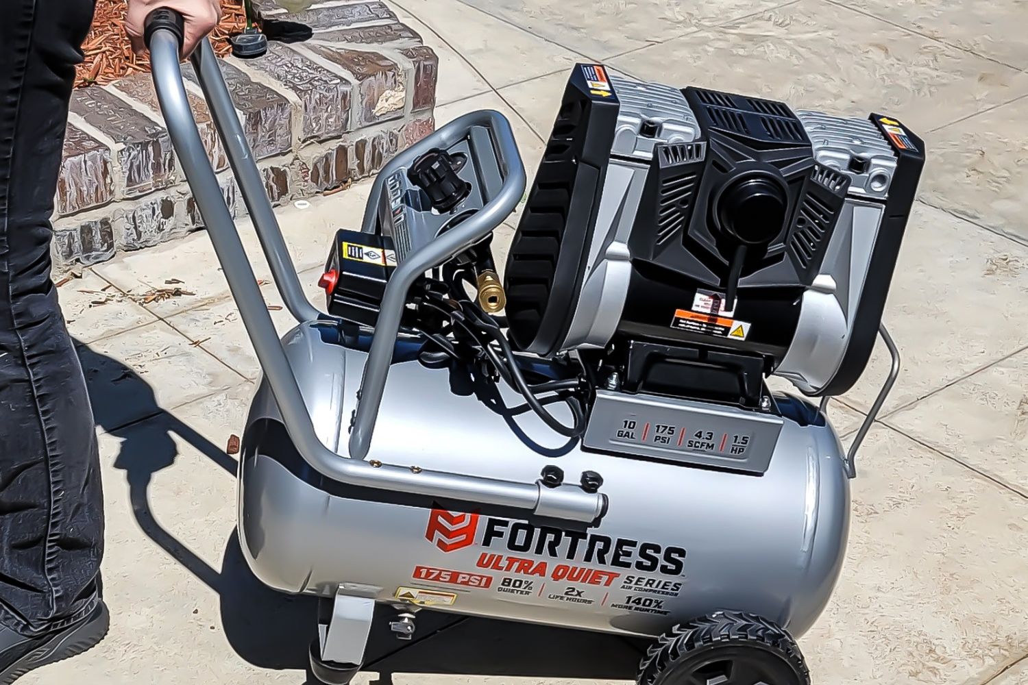 A person moving the Harbor Freight Fortress air compressor by using its wheels and handle