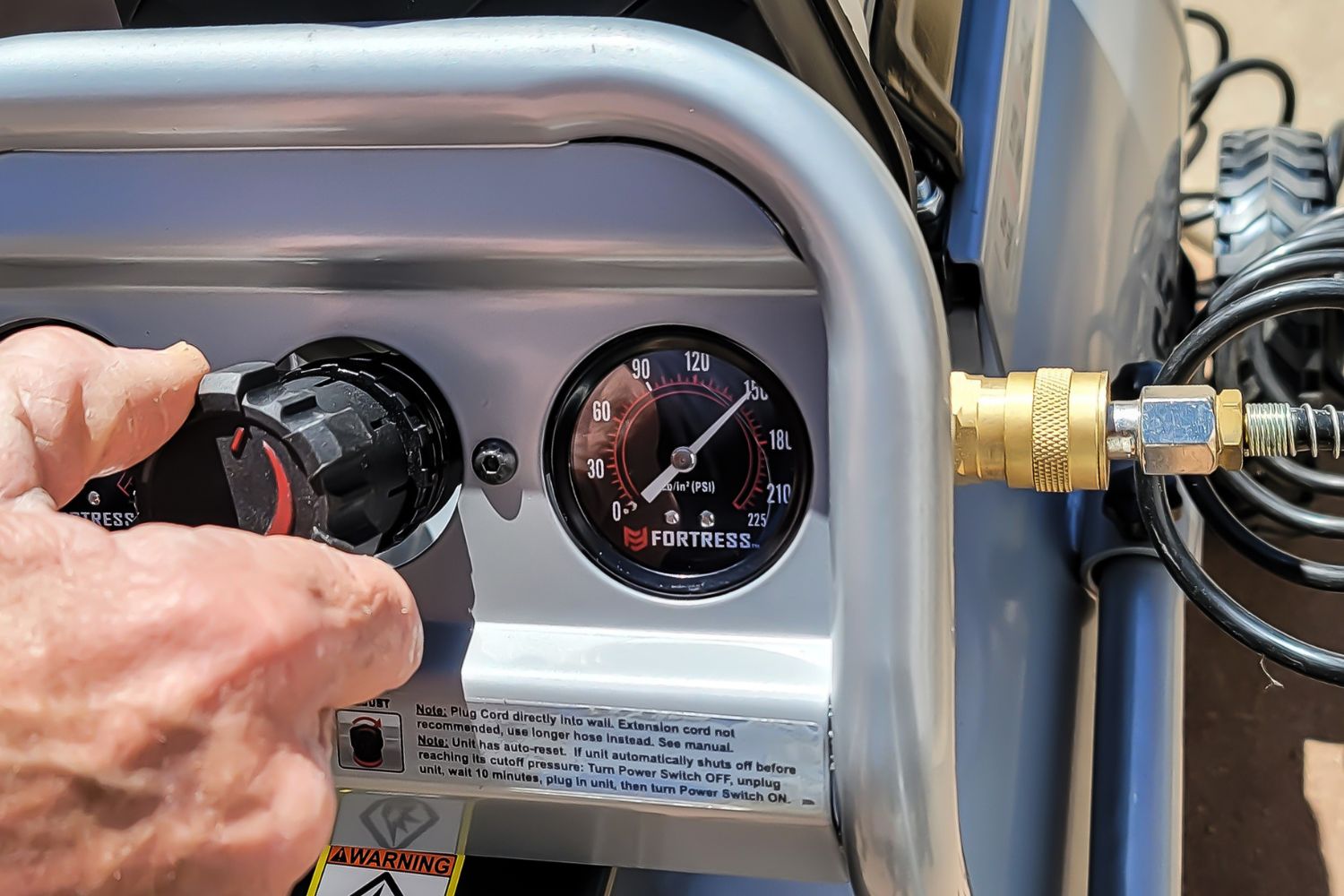 A person adjusts the pressure on the Harbor Freight Fortress air compressor