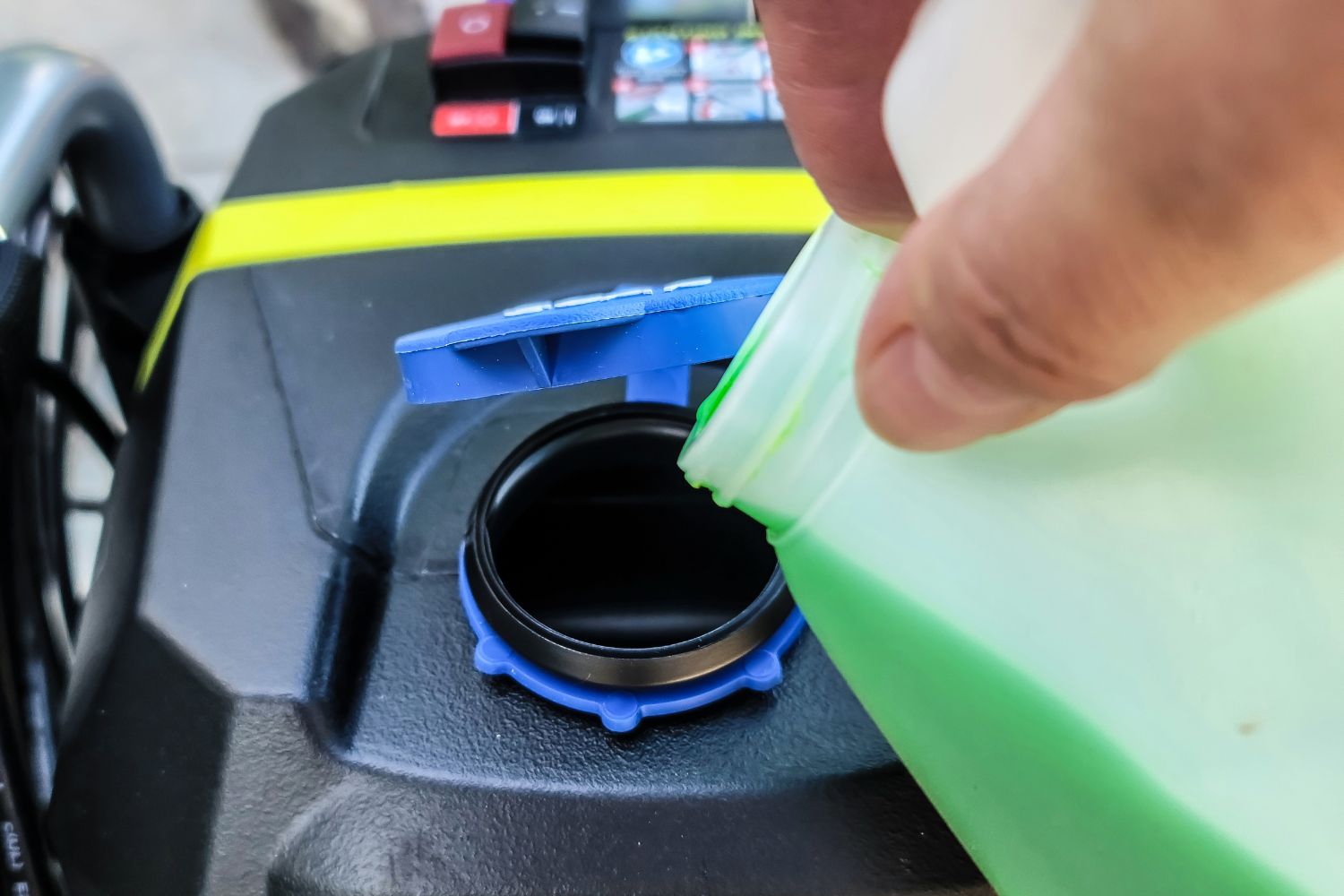 A close-up of someone adding detergent to the Ryobi pressure washer 2000 PSI's onboard soap dispenser
