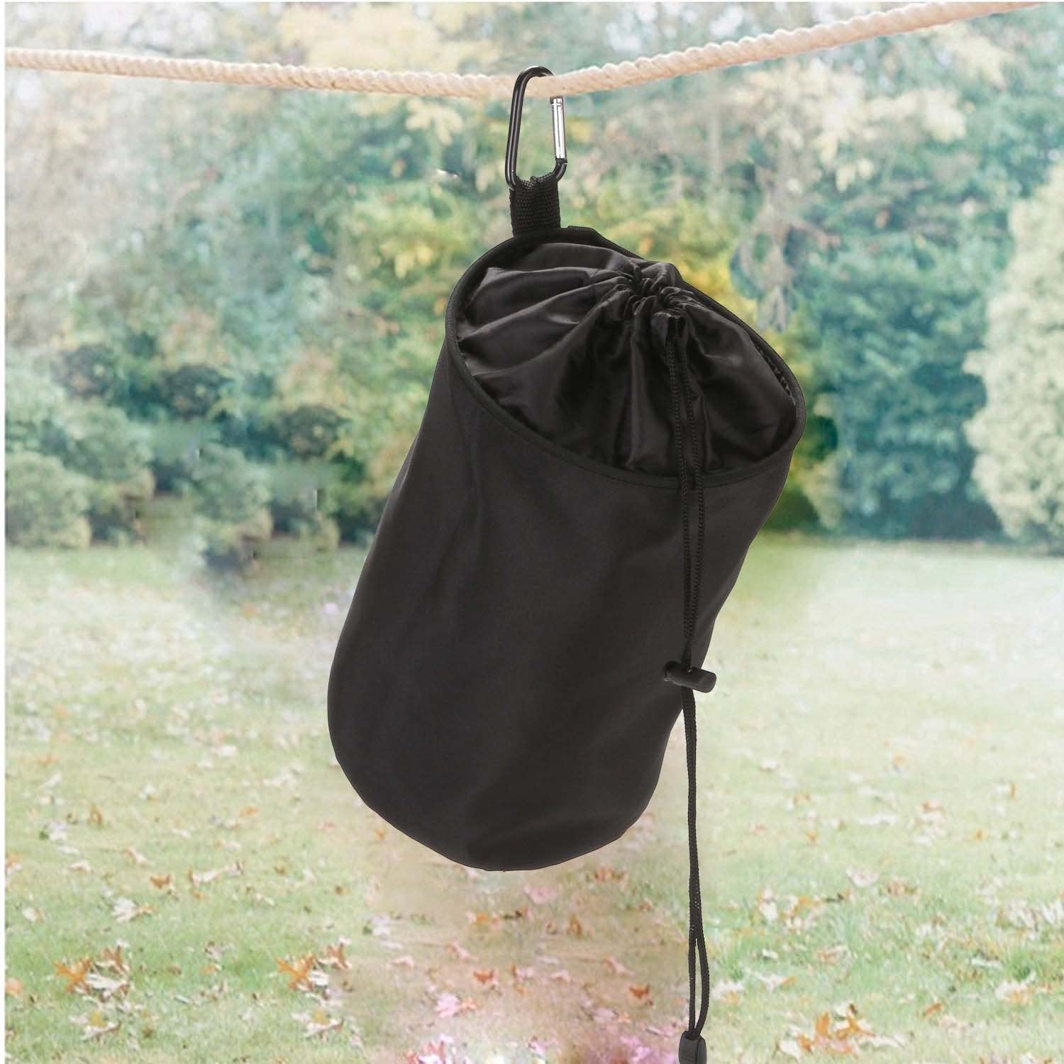 product shot of veamor clothespin bag a black cylindrical bag hanging from a clothesline outside with green grass visible in background