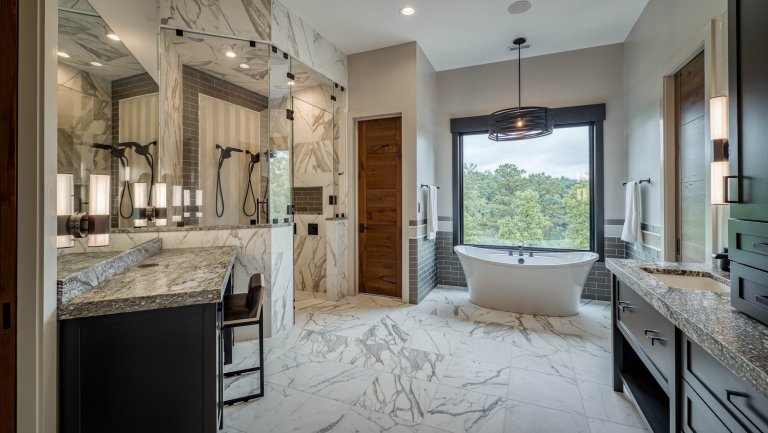 Large, luxurious bathroom with black cabinets and marble flooring.