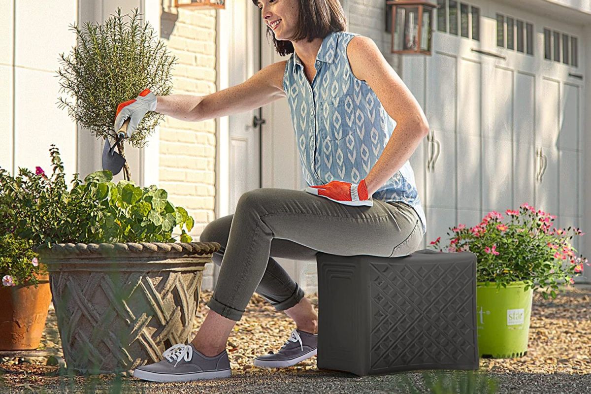 A person seated on the best gardening stool option while working with a potted plant