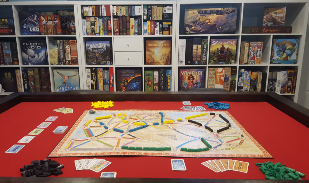 board game set up on table with shelves of games in backround
