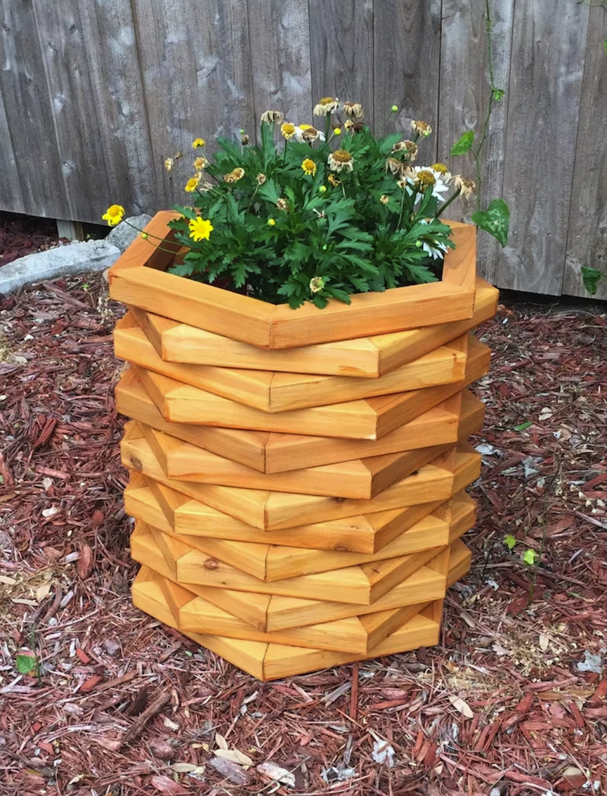 planter box made of stacked hexagonal wooden rights containing flowers in a mulch landscaped backyard