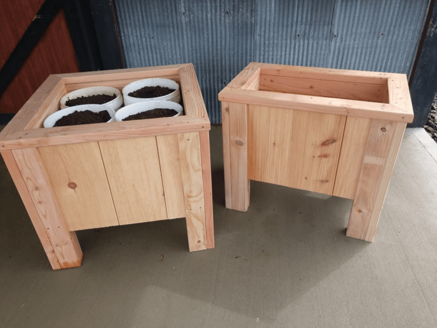 two square wooden planter boxes on legs on with white buckets full of soil inside