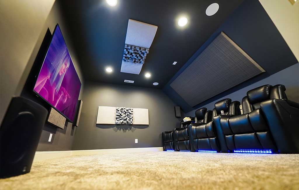 Small home theater with four black leather chairs, acoustic panel, large TV