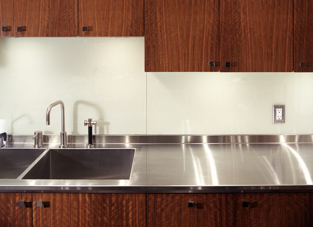 view of kitchen sink with brown cabinets and stainless steel countertops