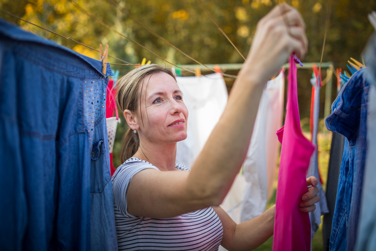 woman hanging bright colored clothing on clothes line outside