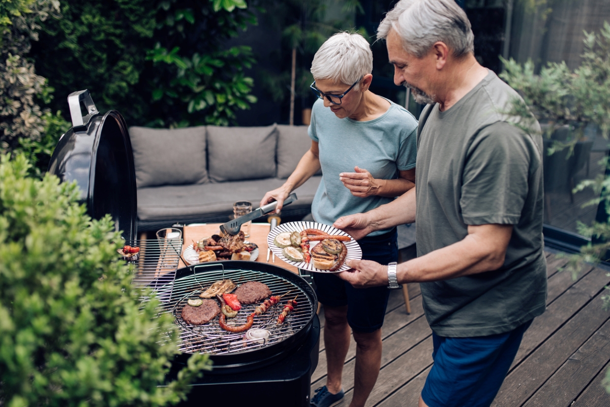 Senior couple cooking on grill outside