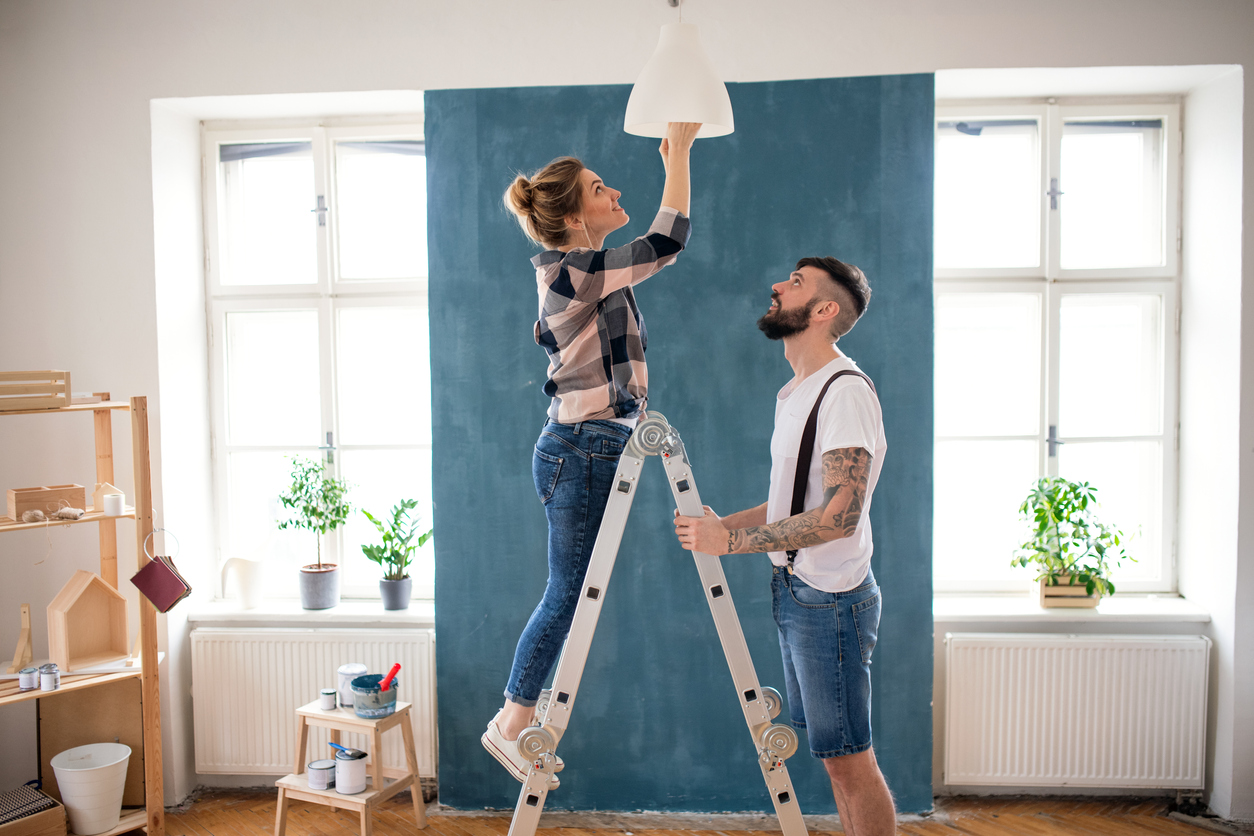 Mid adults couple changing light bulb indoors at home
