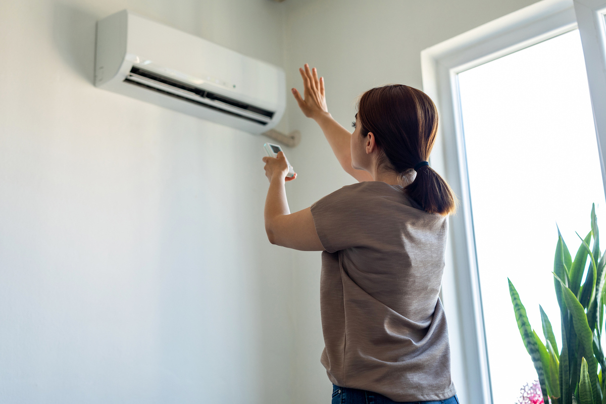woman turning on mini split air conditioning unit for energy efficiency