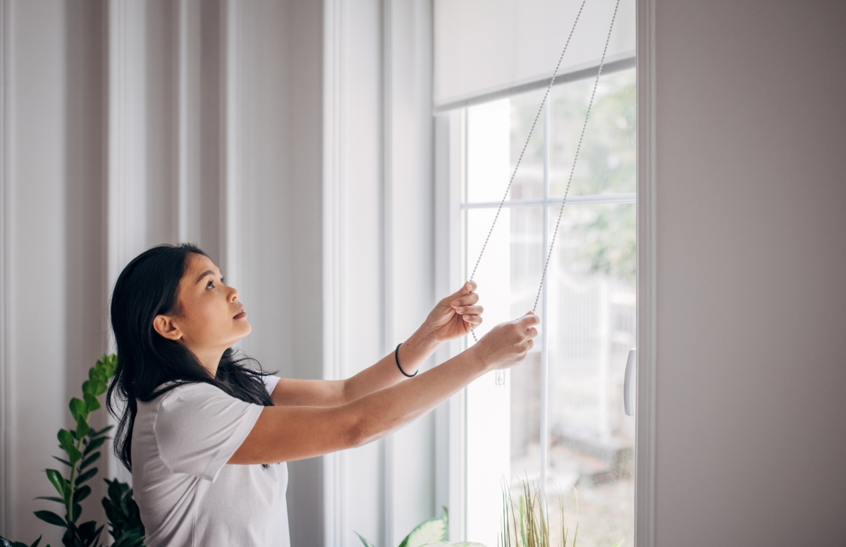 Woman lowering blinds during the day