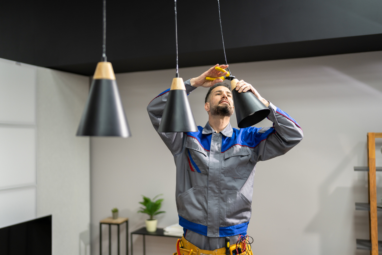 Electrician installing three black conical pendant lights