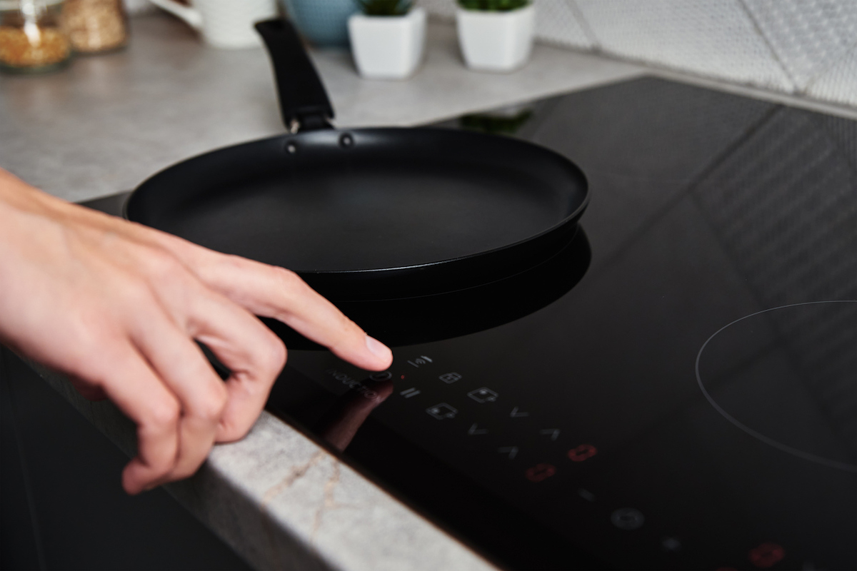 a hand turning on a modern electric stove with induction technology