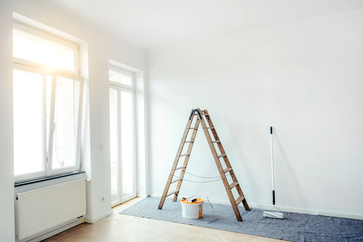 white room with ladder and painting supplies with sunlight streaming through open window