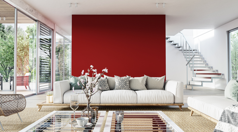 a-bright-red-accent-wall-is-the-background-for-an-airy-living-room-with-white-and-tan-decor