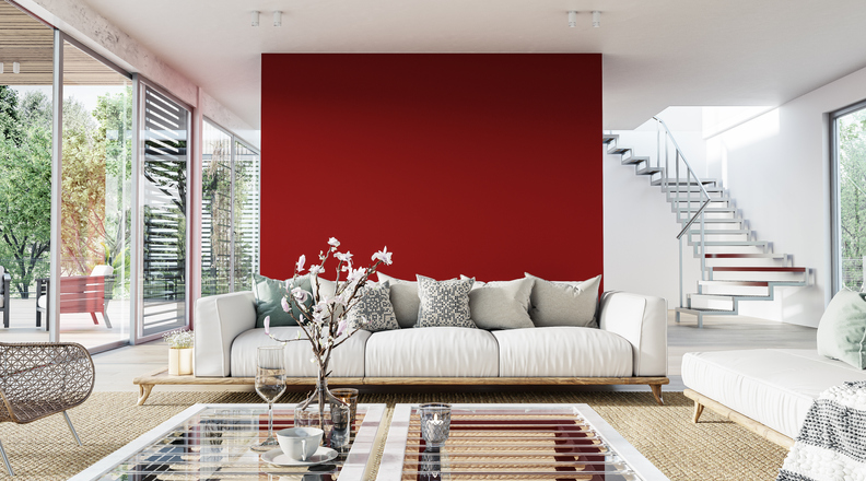a-bright-red-accent-wall-is-the-background-for-an-airy-living-room-with-white-and-tan-decor