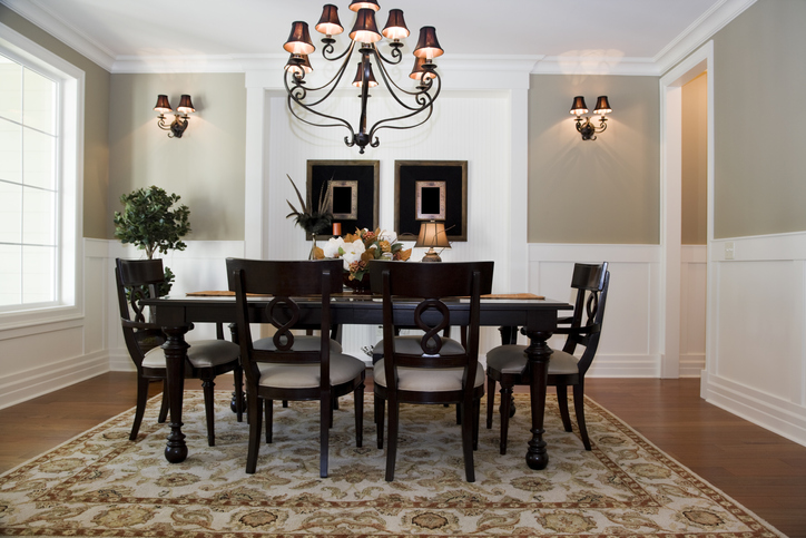 a-traditional-style-black-dinign-table-and-chairs-under-a-black-chendelier-and-in-a-beige-room-with-white-wainscotting