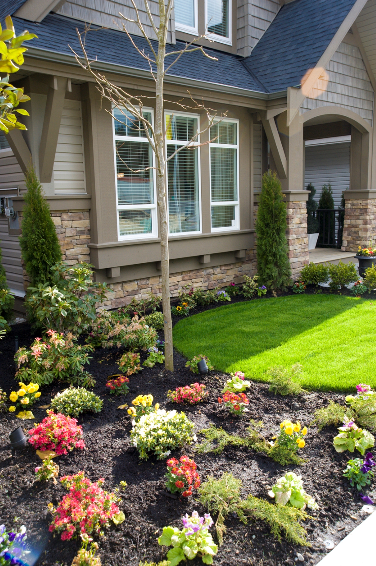 Curb appeal scene with mulched flower beds nedt to a nice house.