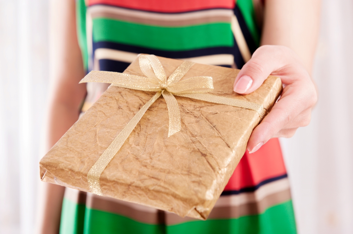 Woman giving gift wrapped in gold paper