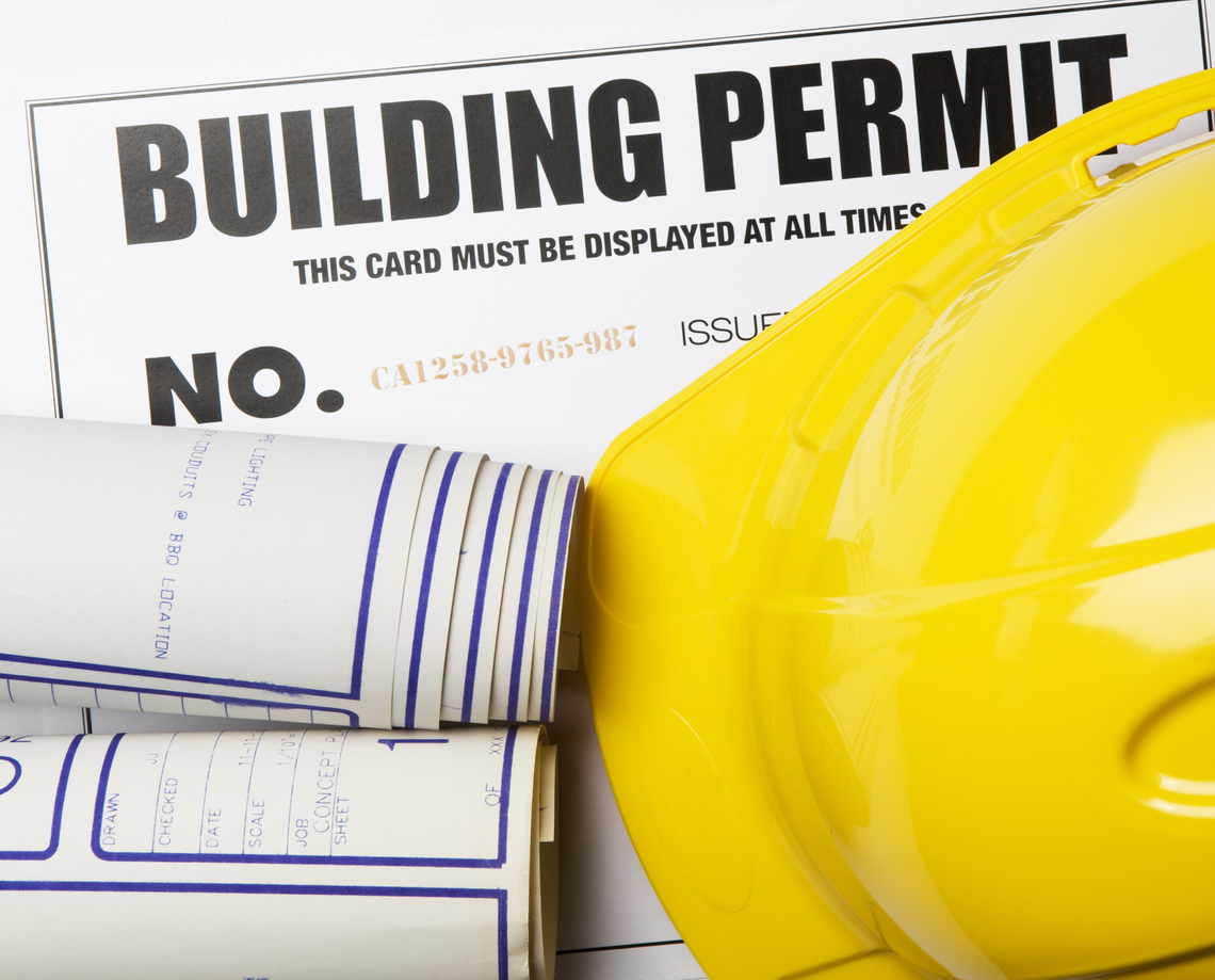Building permit with hardhat and blueprints