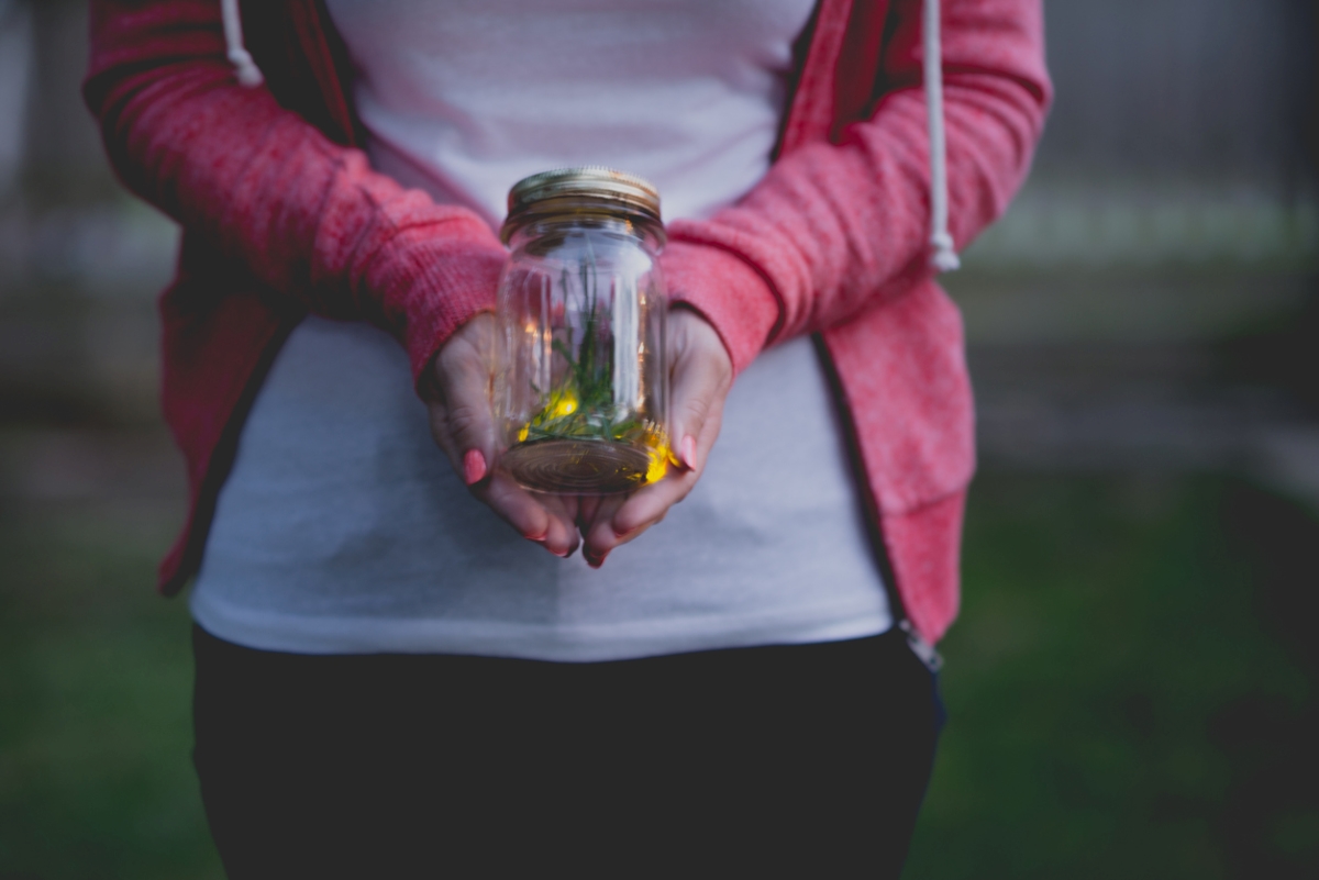 Person holding jar of fireflies