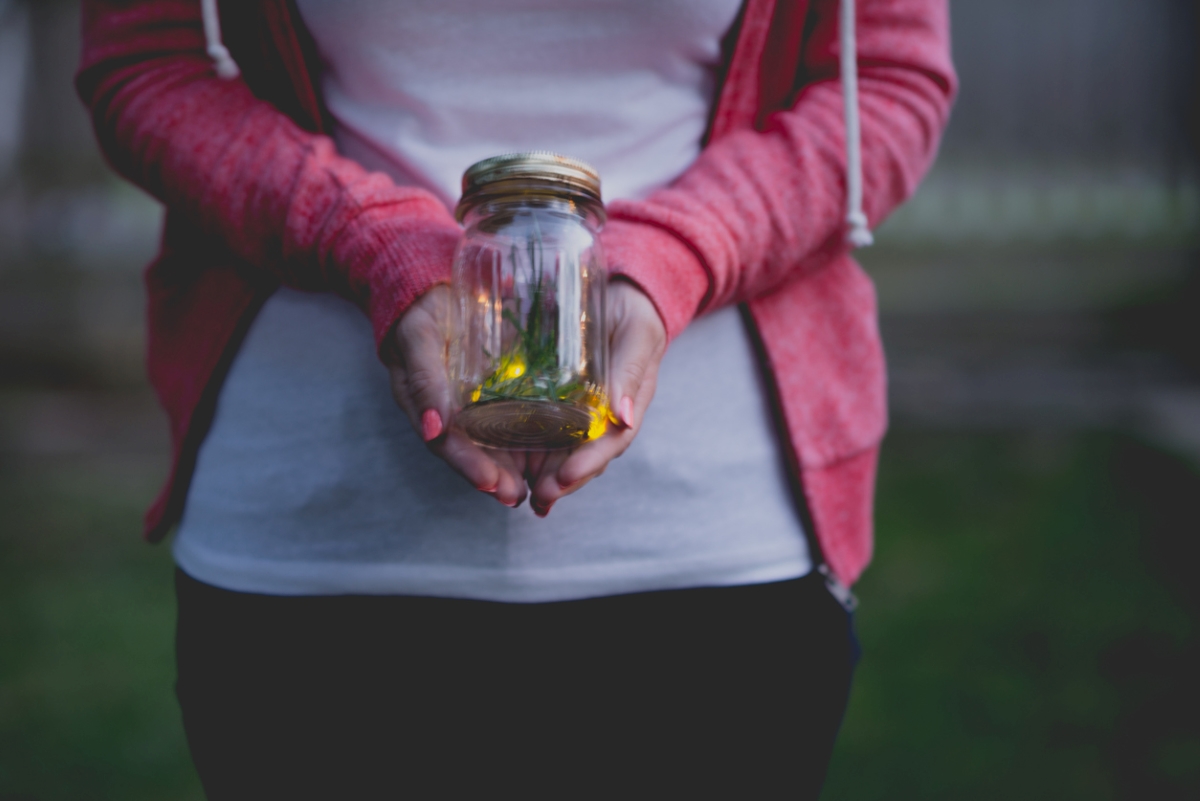 Person holding jar of fireflies