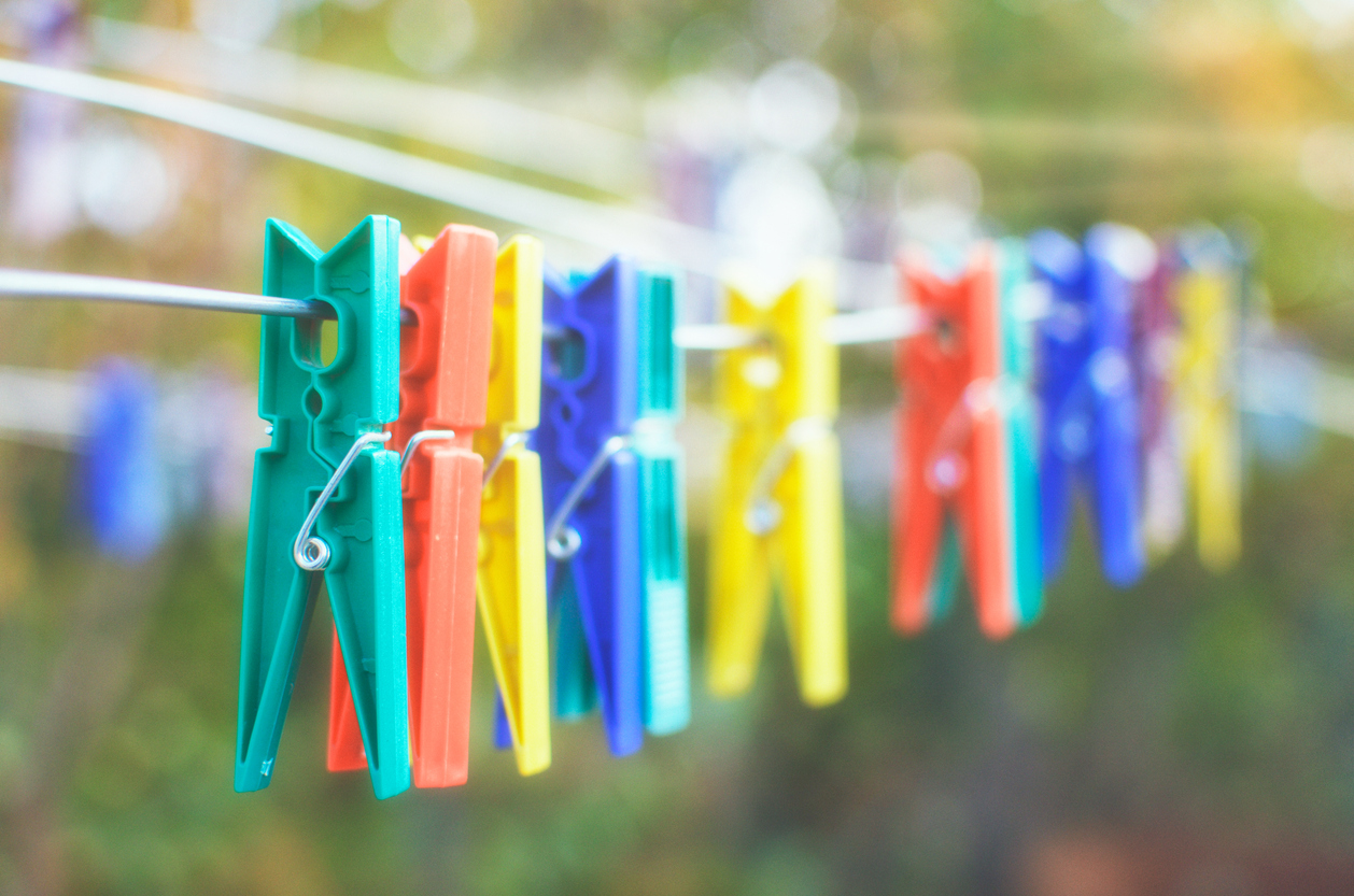 close up of colorful clothes pins hanging in a row on a clothesline outside