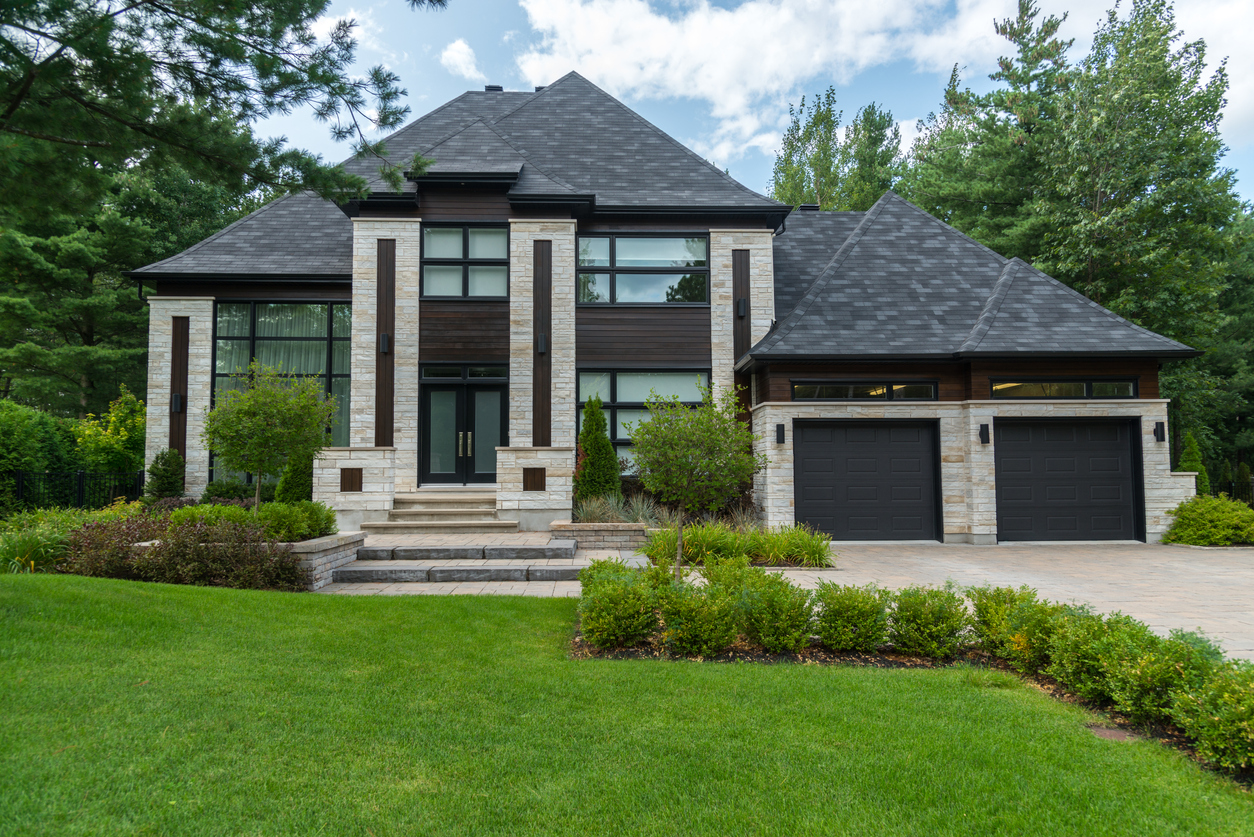 large luxury house exterior made of white stone and dark wood paneling