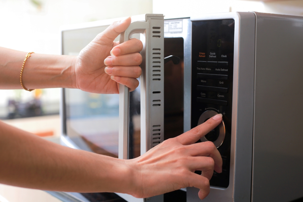 Woman's hands opening microwave and using buttons