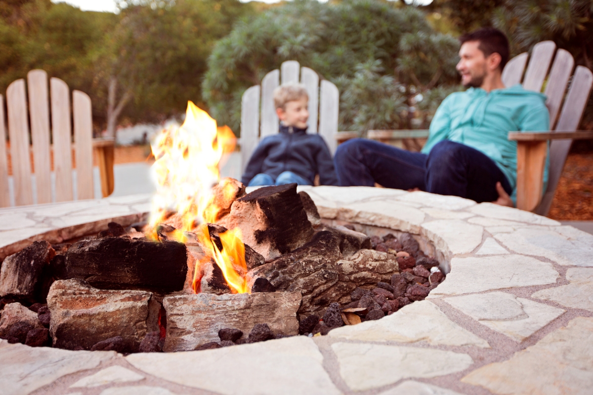 Father and son in chairs behind fire pit
