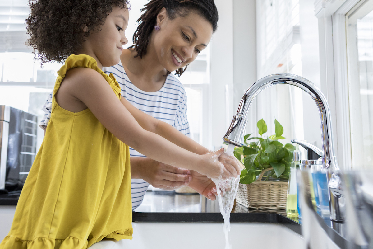mother and daughter washing their hands at the kitchen sink using a low flow faucet