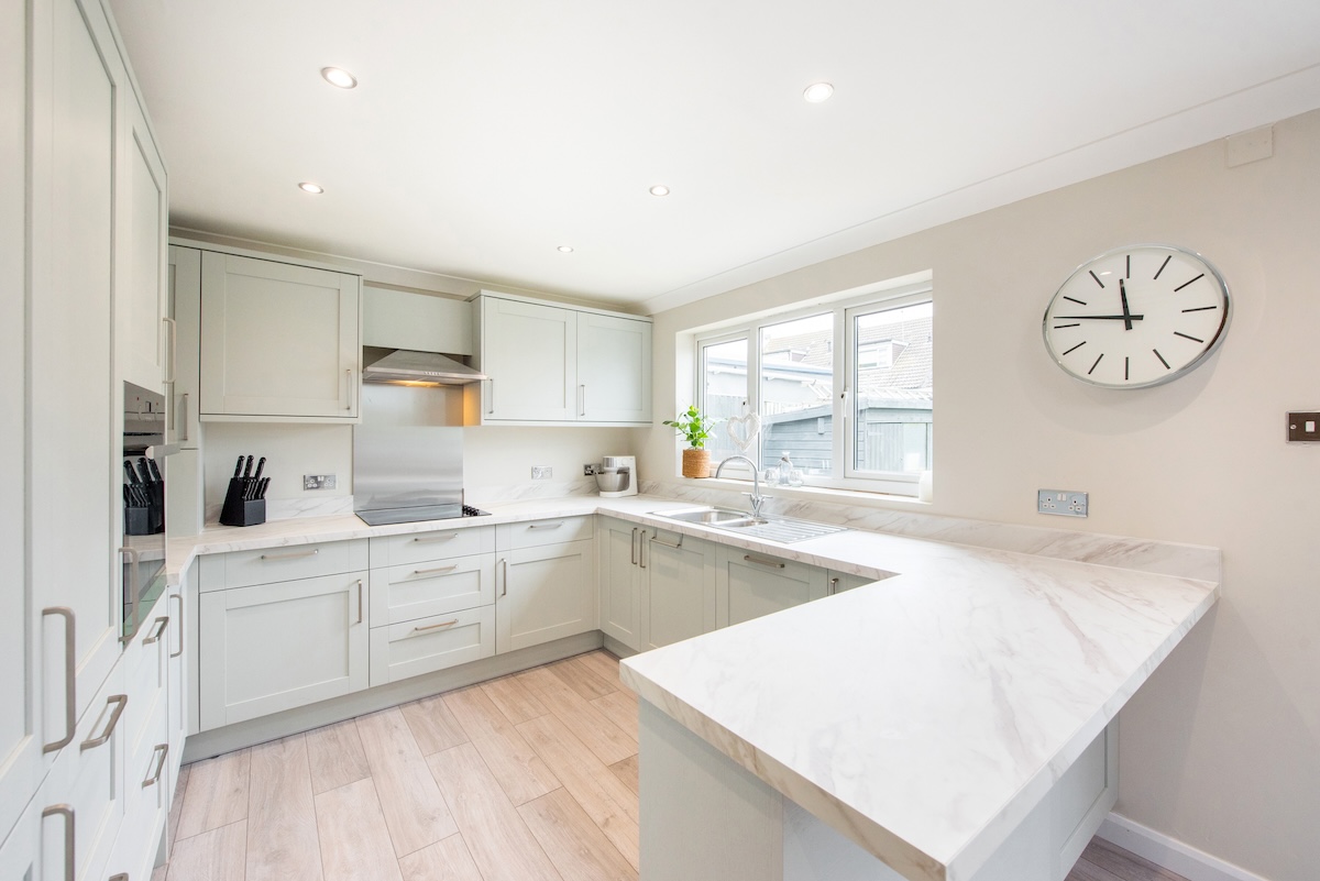 A bright white kitchen with laminate countertops with a marble pattern.