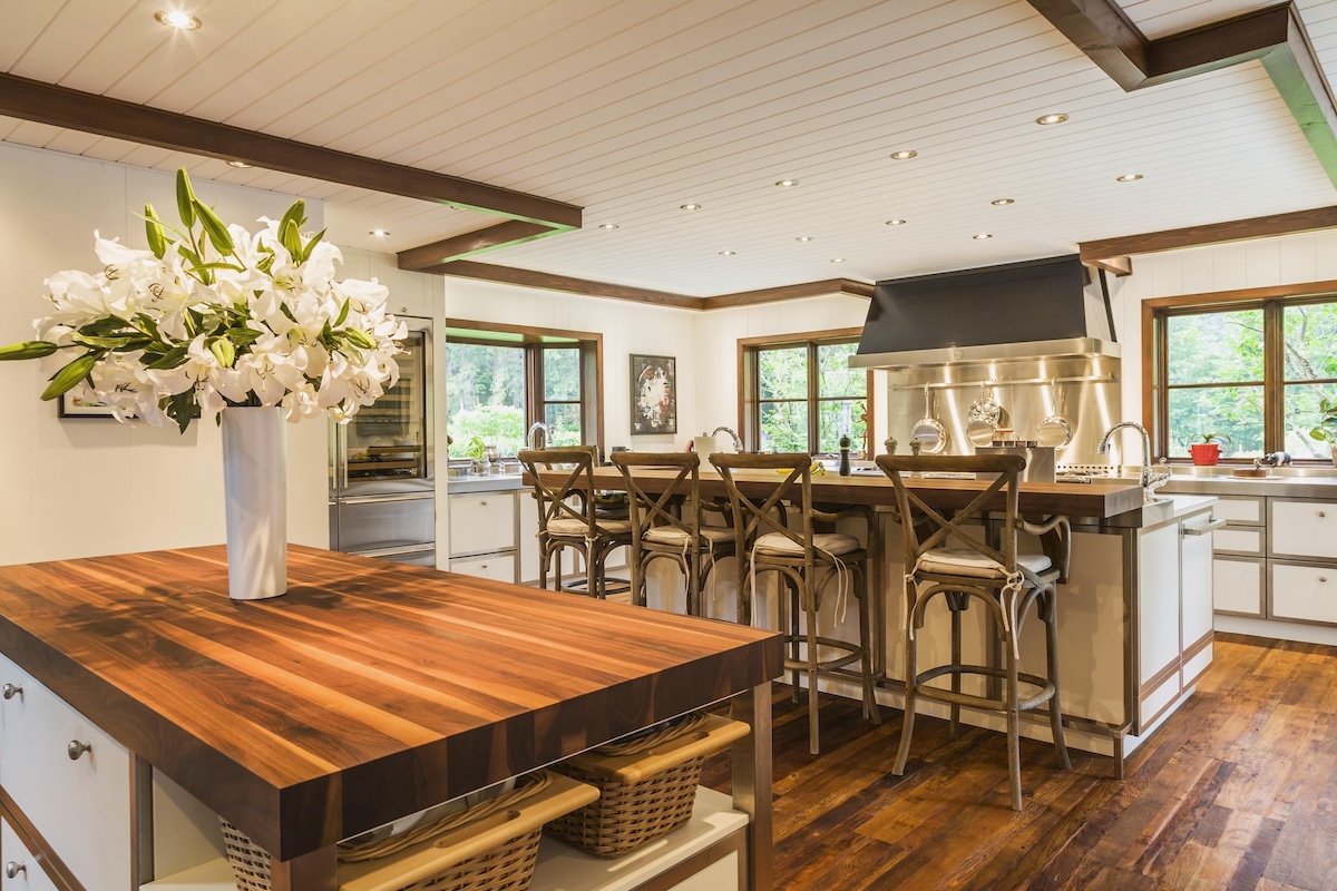 A country style kitchen with an island with butcher block countertops and a breakfast bar with granite countertops.